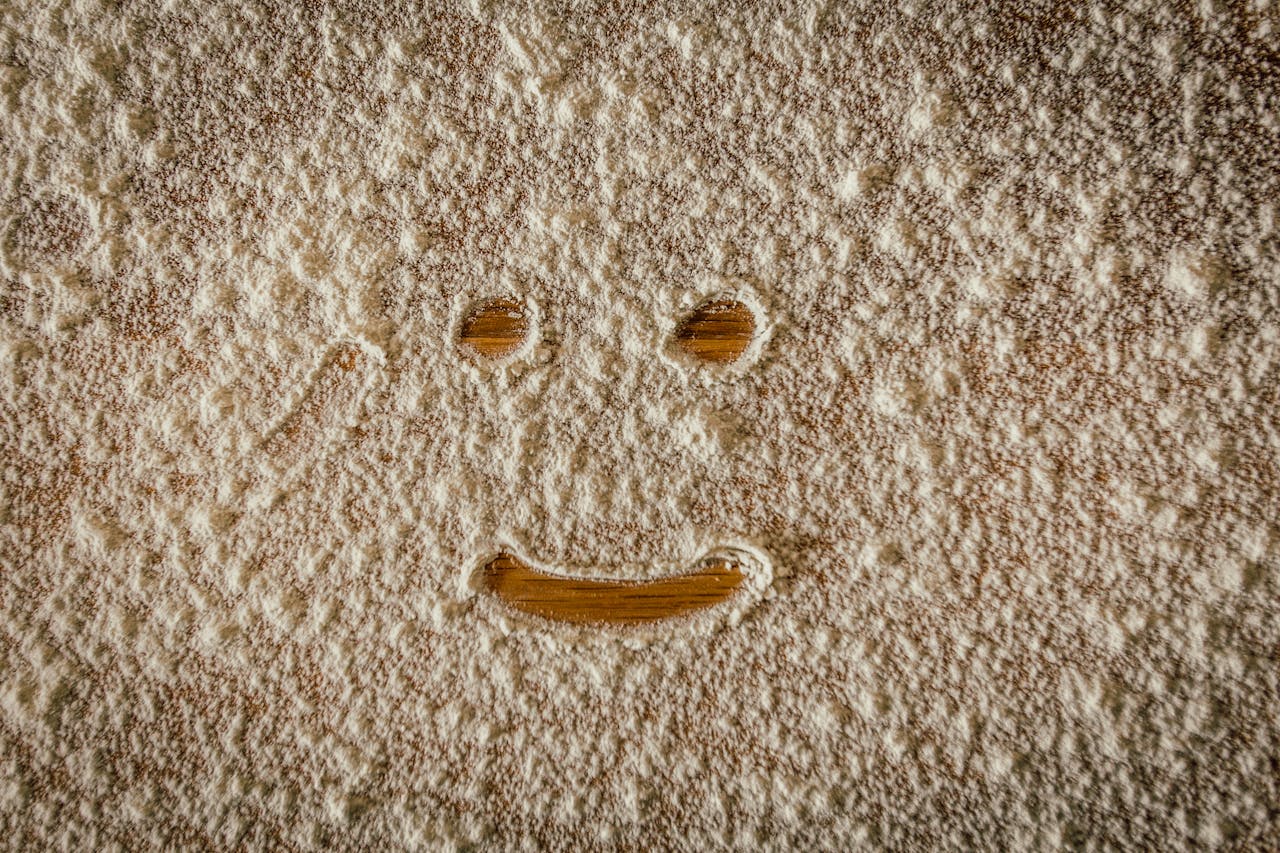 A close-up of a smiley face drawn in flour on a wooden table, evoking creativity and playfulness.
