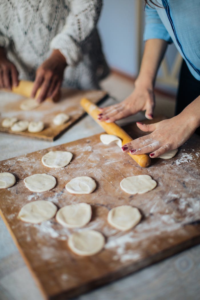 Hands rolling dough on a wooden board for homemade pastries. Perfect food photography.